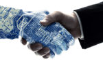 A human hand in a suit shaking hands with a digital hand featuring a circuit board design, representing the collaboration between humans and technology.
