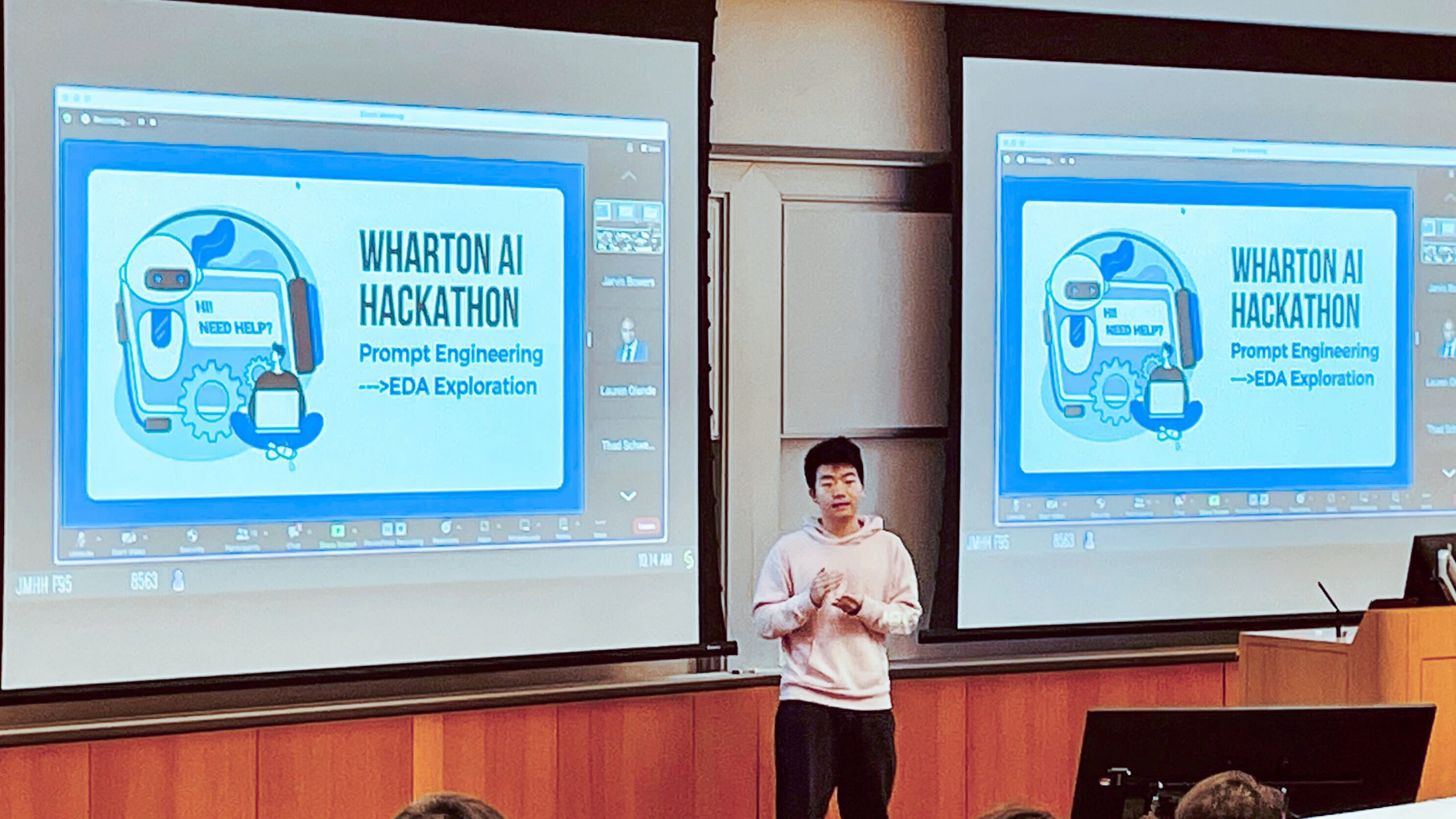 A presentation scene with a person standing in front of screens displaying a slide for the "Wharton AI Hackathon," focused on prompt engineering and EDA exploration.