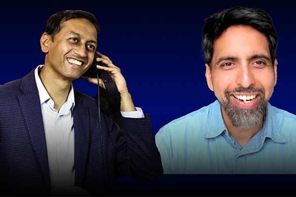 Two people smiling; one is holding a phone, and the other faces forward, both against a dark blue background.